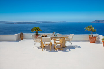 Beautiful Santorini landscape with white architecture and sea view. Sunny summer travel luxury background, cityscape, urban scenic. Idyllic streets, pathway table and chairs as decoration, caldera