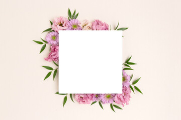 Paper card with border frame made of eustoma flower on a beige background. Springtime composition for 8 March with copyspace.