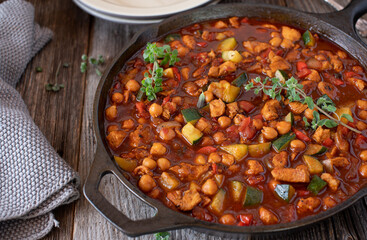 Chickpea stew with chicken breast and mediterranean vegetable in a rustic skillet