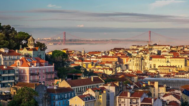 Timelapse 4k footage, Lisbon, Portugal, morning sun rays light up downtown, fog going up Tagus river and bridge of 25th April, tourist destination.