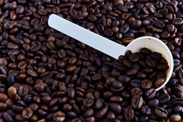 Coffee beans and a plastic spoon scattered on the table.