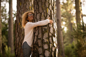 Happy adult lady hug tree trunk in outdoor leisure park activity. Concept of environment and...