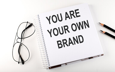 Notepad with text YOU ARE YOUR OWN BRAND White background. Business concept