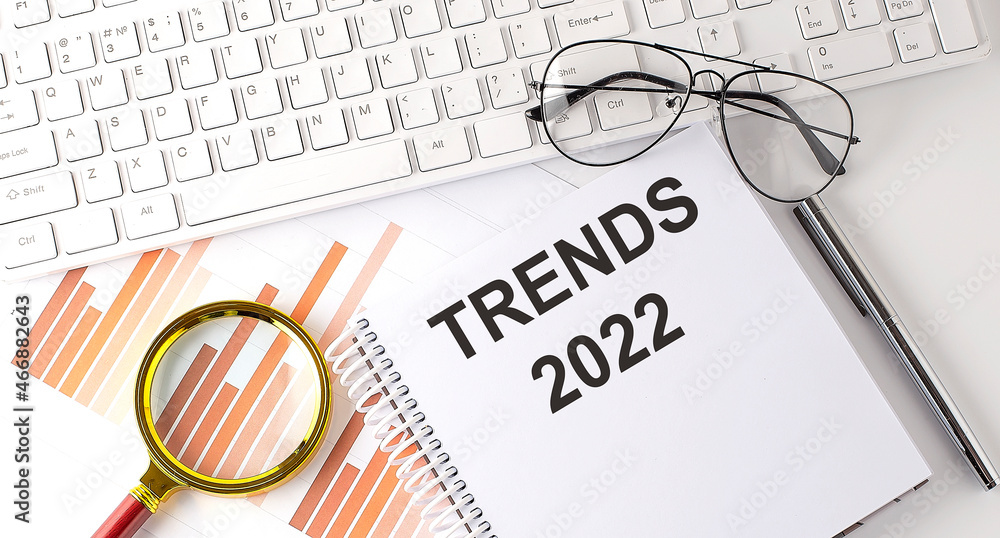 Aufkleber trends 2022 text written on a notebook with keyboard, chart,and glasses