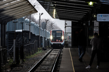railway station with arriving train on gray autumn day 