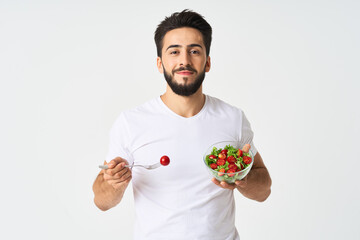 Cheerful man in a white T-shirt with a plate of light green and a healthy meal