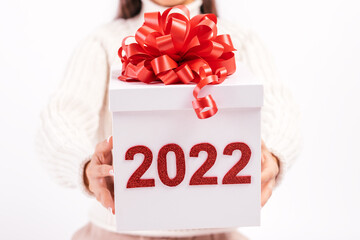 Close up of young woman on a white background holding a white gift box with red bow and the numbers...