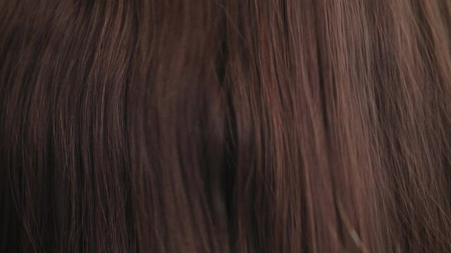 haircare, comb moves along beautiful healthy long flowing brown hair close up, texture