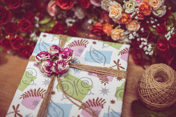 Gift box and Christmas decorations background, flat lay. Space for text. Beautiful Christmas present boxes on wood floor with rose and colorful flower. Happy new year concept. lovely valentine's day.