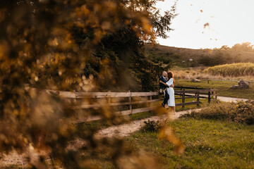 A tight hug of a newly married couple on a ranch against a beautiful sunset