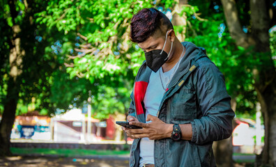 Man with a mask texting with his phone, young man with a mask texting with his cell phone, close up of a young man with a mask texting