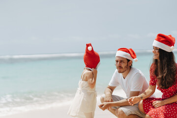 Obraz premium Happy family in Christmas Hats having fun on white beach on tropical island