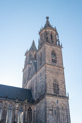 Fototapeta na wymiar Bell and clock tower of Magnificent old Cathedral in Magdeburg, Germany, at blue sky and sunny day. Concept historical and religious heritage.