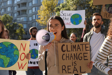 Group of people with posters protesting against climate change on city street - obrazy, fototapety, plakaty