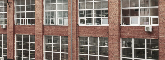 Large windows of an old production building. Red brick walls, glare on glass windows. Panoramic view. Loft concept.