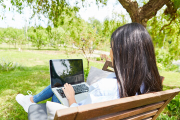 Woman on laptop PC during video chat in the green garden