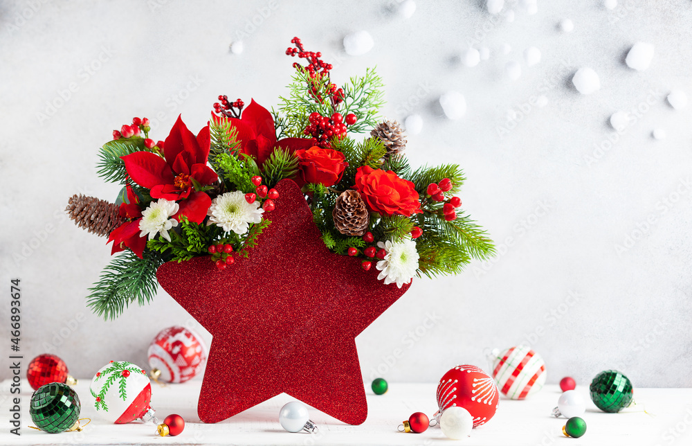 Poster festive winter flower arrangement in vase of red star shape and christmas decorations on table.