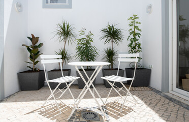 Internal patio courtyard with white metal table and chairs and planters - obrazy, fototapety, plakaty