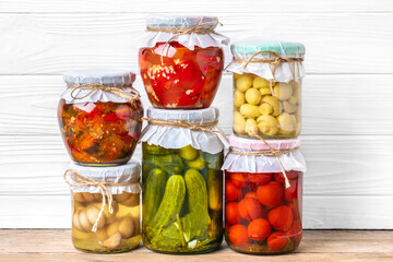 Homemade pickled cherry tomatoes, cucumbers, champignons, garlic, eggplant, red peppers in jars on...