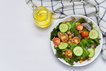 vegetable salad with olive oil and napkin on the whhite background. horizontal view. Free space for menu. Vegetarian diet.