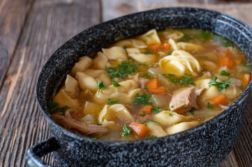 Pot with chicken noodle soup. Cooked with tortellini