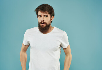 bearded man in white t-shirt emotions displeasure upset blue background