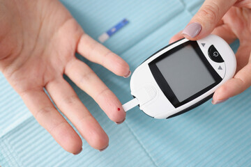 Close-up of female hands holding glucometer with strips