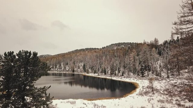 Altai, Siberia, Russia. A lonely wild empty mountain lake in winter with white snow-capped mountains on the background. Snow-covered forests, a highway, reflections in the water. Freedom, loneliness