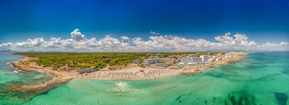 Wide panoramic aerial drone photo taken on the beautiful island of Majorca Mallorca in Spain showing the beach and sea front of the beach of Can Picafort on a bright sunny summers day
