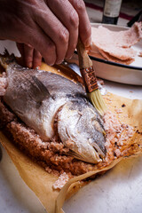 Sea bass baked in sea salt dorado crusted from Mediterranean lubina. Chef hands cooking food for healthy lunch or dinner.