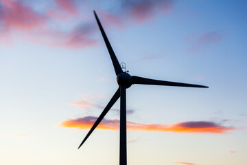 Close up of a silhouetted wind turbine, against a colourful sky