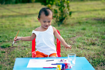 girl with dirty hands and fingers, using paintbrush painting on paper and her Tank top.