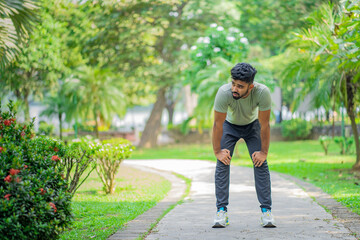 Tired young man runner taking a rest after running hard at the park