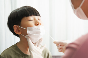 Covid 19 testing before back to school. An asian mom gently do a nose swab rapid test for her...