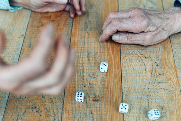 elderly people play at the table with dice - focus on the hand to the right of the photo