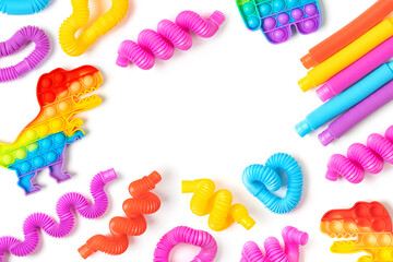 Trendy kids toys —  colorful  pop-tubes and pop-it on white background with copy space. Set of different forms and colors corrugated pipe and  fidget finger toys. - obrazy, fototapety, plakaty