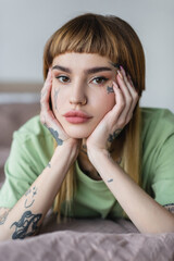 pretty young woman with tattooed face and hands looking at camera at home