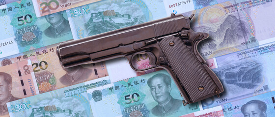 Pistol on Chinese Yuan banknotes background. Criminal money, mafia and corruption in China concept