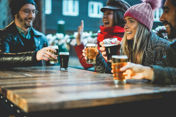 Young people having fun drinking beer at bar restaurant - Soft focus on right girl hand holding...