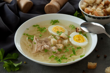 chicken soup with noodles, egg, herbs and croutons