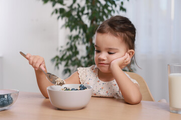 Cute little girl refusing to eat her breakfast at home