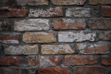 Grey white black red orange old vintage brick wall background. Rustic cemented dark brick house wall texture with grunge surface. Shabby Building Facade With Damaged Plaster. Aged weathered exterior