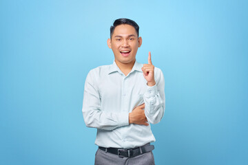 Naklejka premium Happy young handsome businessman having a creative idea and looking camera on blue background