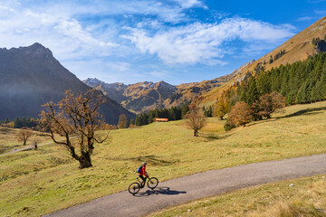 pretty woman riding her electric mountain bike in the mountains of Hinterstein Valley in the upper...