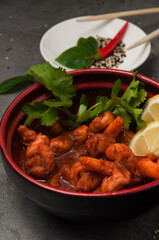shrimp in hot sauce garnished with lemon, coriander, and hot chili pepper