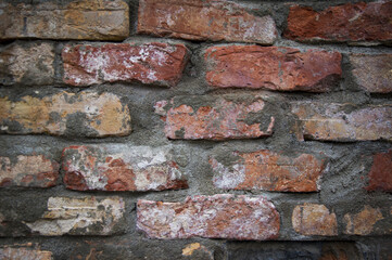 Grey white black red orange old vintage brick wall background. Rustic cemented dark brick house wall texture with grunge surface. Shabby Building Facade With Damaged Plaster. Aged weathered exterior