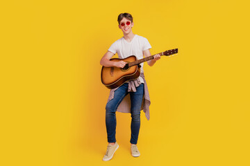 Full body photo of young excited man play guitar concert performance hipster isolated yellow color background