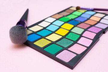 Palette with eyeshadows and makeup brushes on pink background. Flat lay. Blog about cosmetics and fashion. Set of products for makeup.