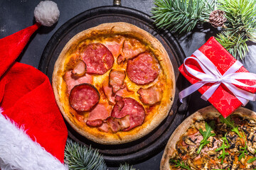 Christmas decorated background with pepperoni and mushrooms pizza, Delivery and restaurant Xmas Lunch and party menu, Santa delivers pizza for Christmas, black concrete background top view copy space
