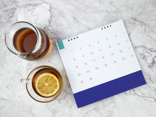 Lemon tea and calendar on marble texture background.